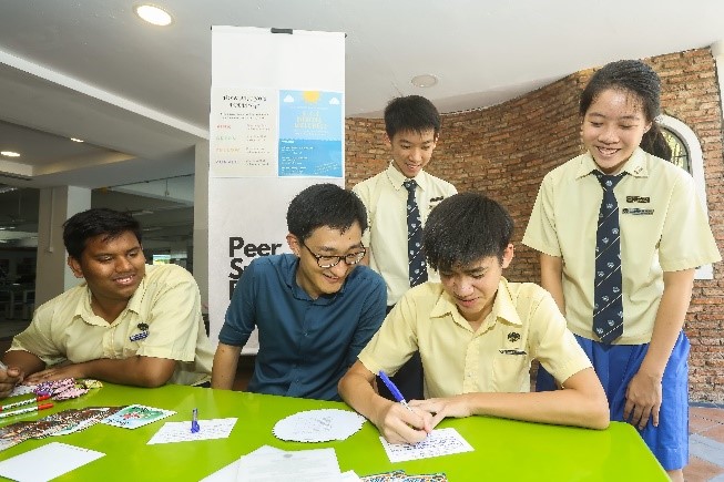 Students writing postcards to show appreciation to their parents with Mr Joel Tan.